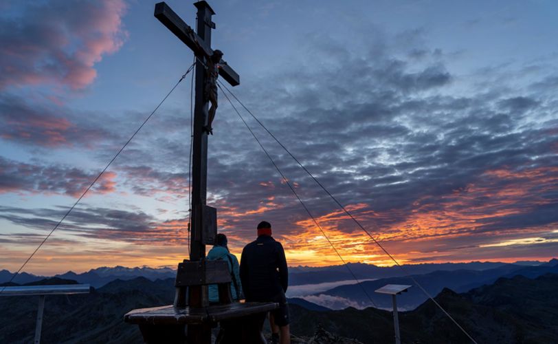Zwei Wanderer beobachten den Sonnenaufgang von der Kassianspitze aus