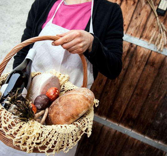 Ein Korb mit Osterbrot, Wein und bunten Ostereiern